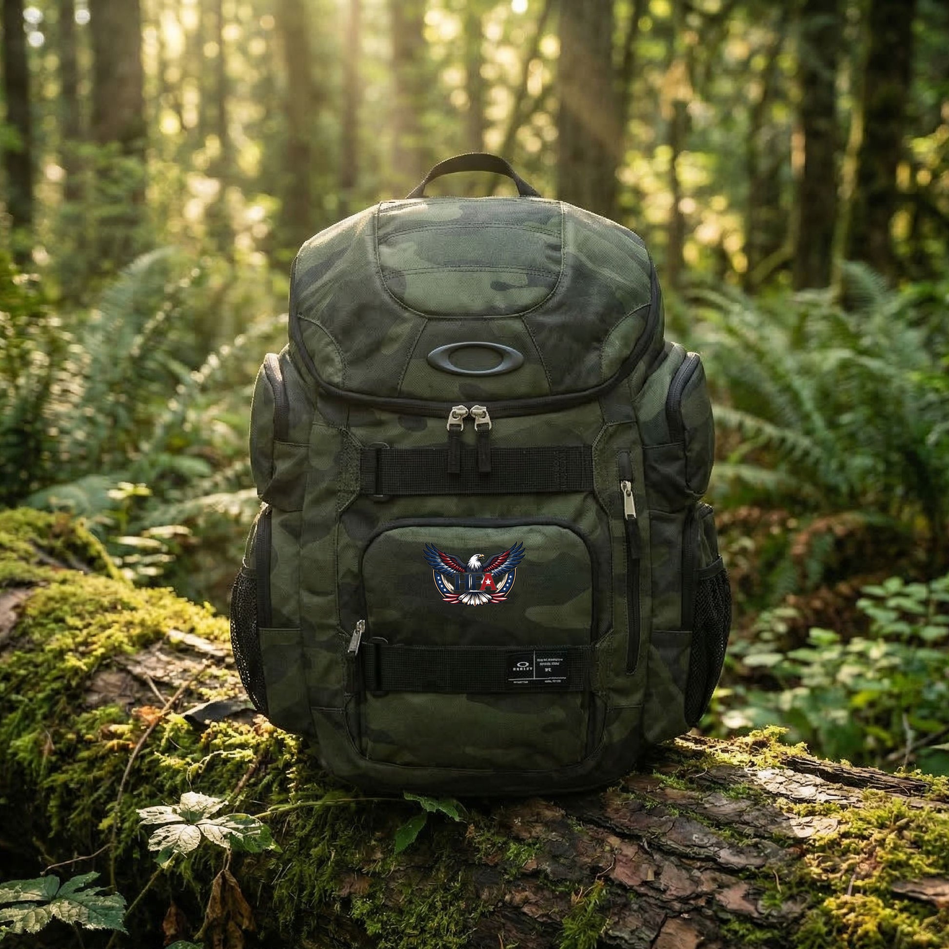 Green camouflage backpack with a logo on a log in a forest setting