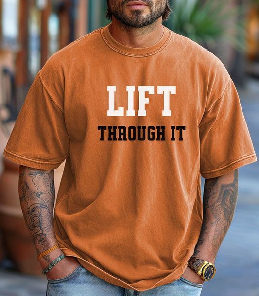 Man wearing a brown t-shirt with 'LIFT THROUGH IT' text, standing outdoors.