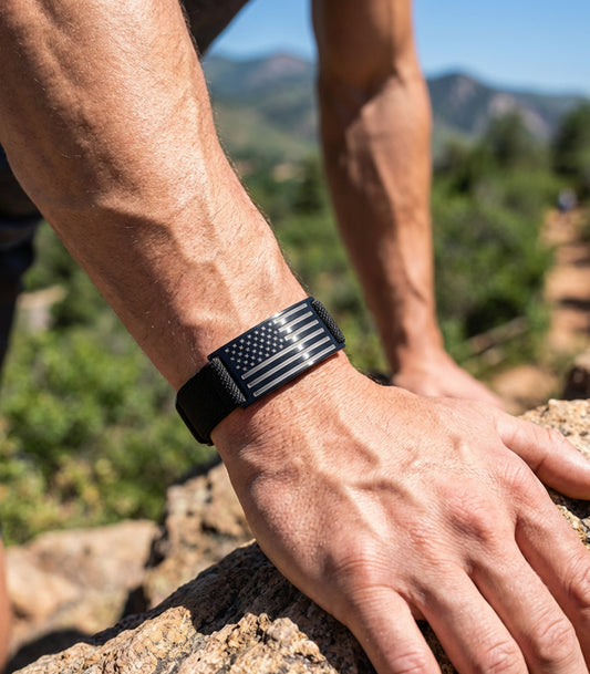 Person wearing a black wristband with an American flag design on a mountainous background